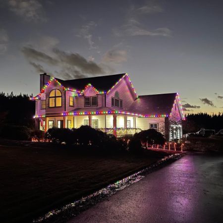 Large house decorated with colorful Christmas lighting in Portland, OR. Candy canes line the driveway, enhancing the festive holiday atmosphere at dusk.