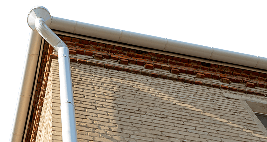 Close-up of a building's brick facade with a white commercial gutter system installed. The gutters run along the roofline, providing essential drainage and preventing water damage.