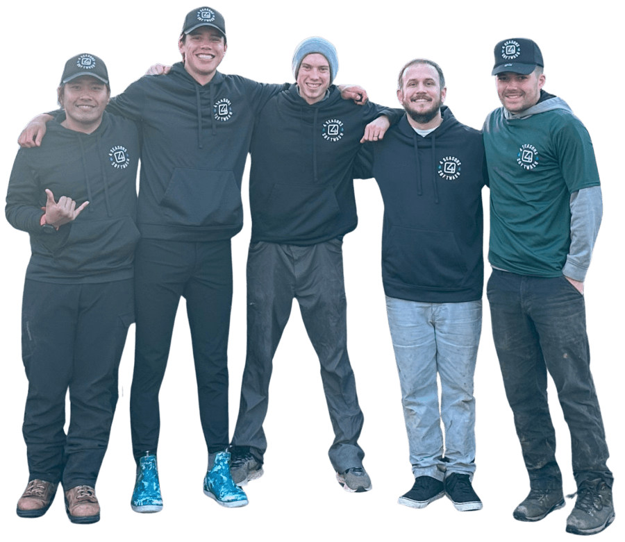 Five young men, likely a pressure washing team, stand shoulder-to-shoulder, smiling. They wear branded "Seasons Software" hoodies and hats, posing outdoors in work clothes.