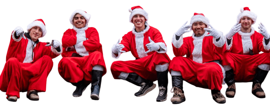 Five friends dressed in Santa suits squat in a row, flashing hand signs and smiling. Festive Christmas lighting fun in Portland, OR.