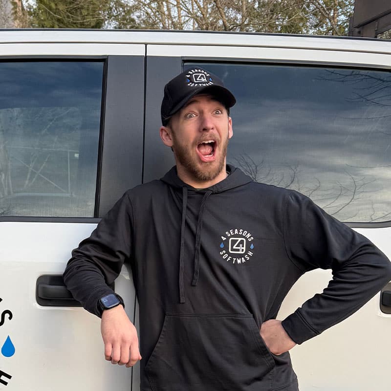 Enthusiastic man in a "4 Seasons Softwash" hoodie and cap stands by a company truck, expressing excitement. Part of the "Meet Our Team" series.